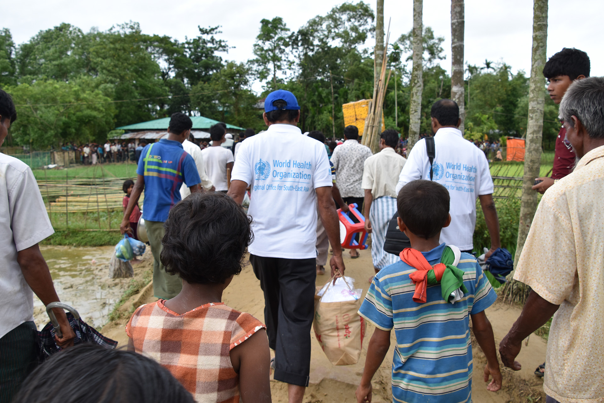 responding-coxs-bazar a group of people including some children walking with their backs to the camera
