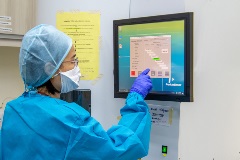 Automatic gene extraction machine for COVID-19 technician in protective gear looking at monitor