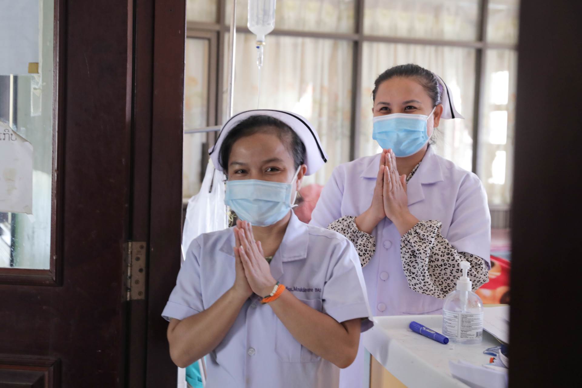 0Y7A2358 edited Two nurses with hands joined greet patients in a clinic