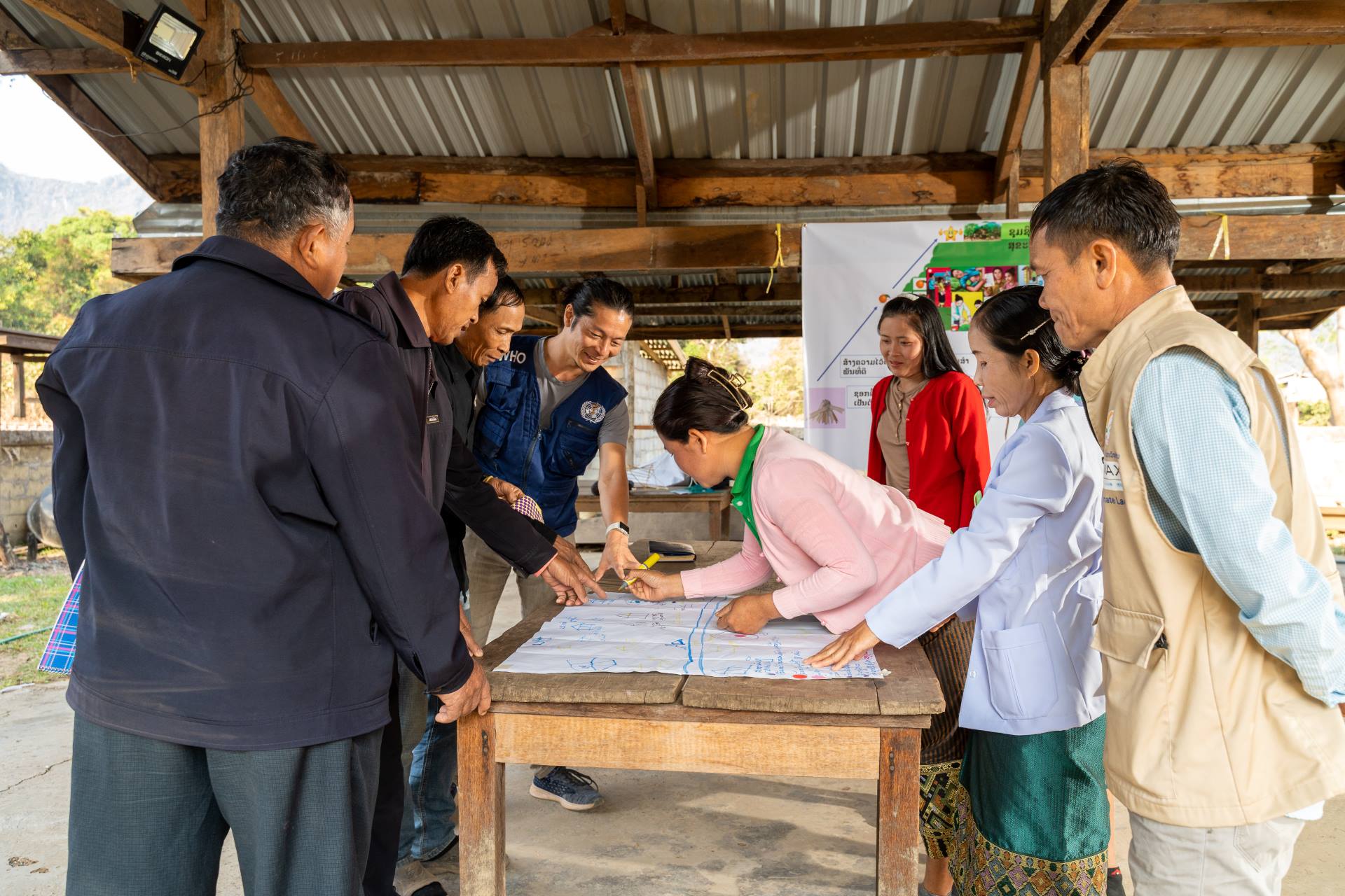 20230219_CONNECT_Savannakhet-1527 Health workers stand around a table and map out village health services