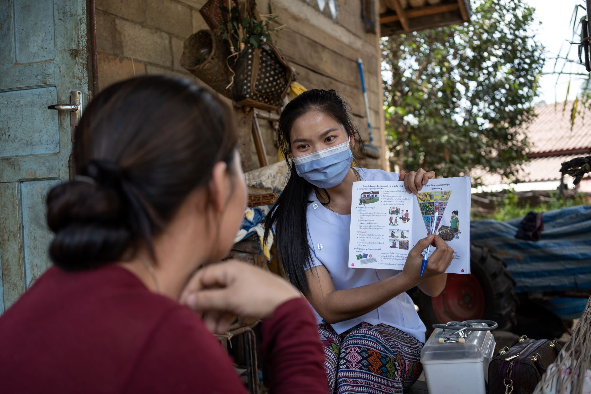 WP49440 A health worker holds a pamphlet to explain nutrition to a young female.