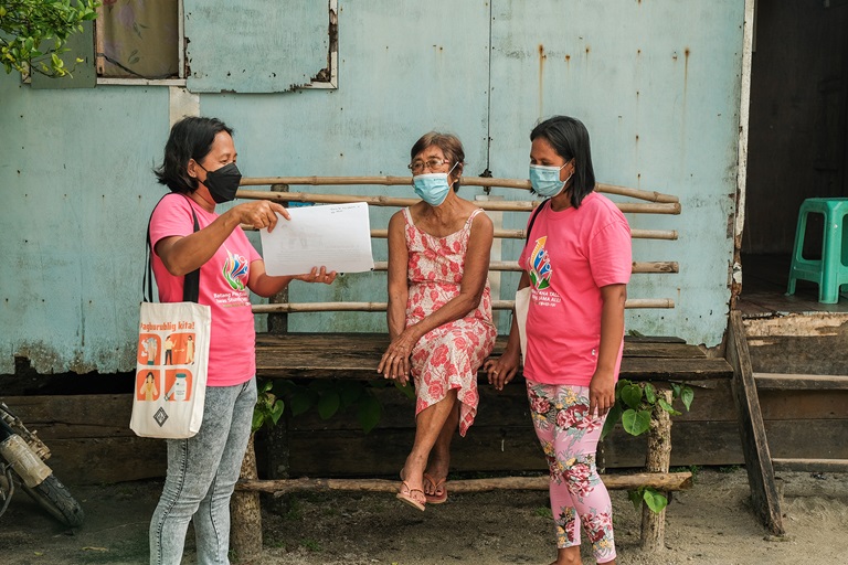 2021 Barangay Health Worker Lorena Ida (left) shares the benefits of COVID-19 vaccines to a senior citizen in Manicani Island, Eastern Samar.